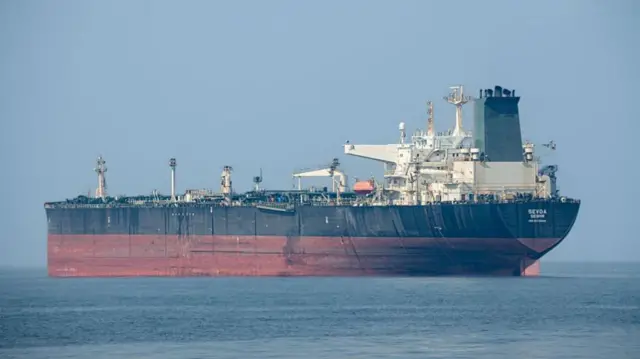 Un tanquero petrolero pintado de rojo y negro flota en medio del mar.