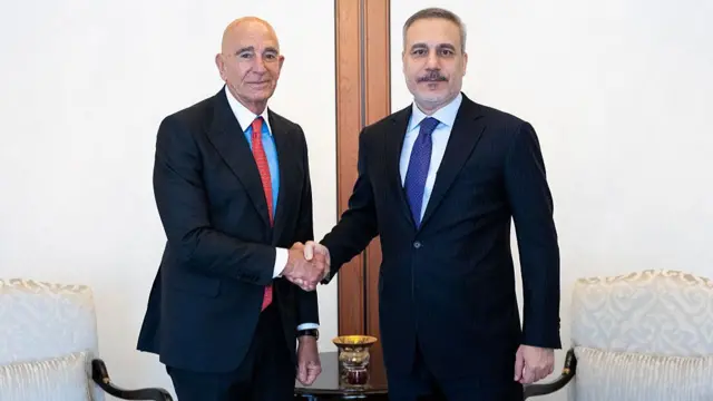 Dışişleri Bakanı Hakan Fidan ve ABD Büyükelçisi Tom Barrack ayakta el sıkışırken kameralara bakıyor