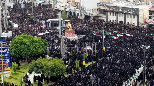 Снимок с воздуха, на котором запечатлены скорбящие люди с иранскими флагами и портретами, собравшиеся на похоронах детей, погибших в результате ударов США и Израиля по начальной школе в иранской провинции Хормозган, 3 марта 2026 года в Минабе, Иран.