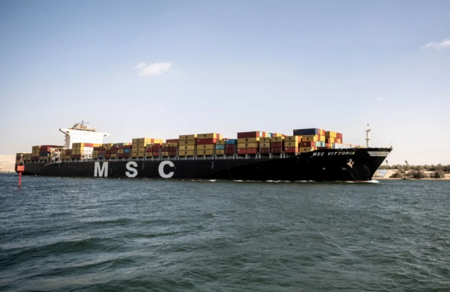 سفينة حاويات تابعة لشركة البحر الأبيض المتوسط للشحن تعبر قناة السويس في النهار باتجاه البحر الأحمر، والموج هادئ.