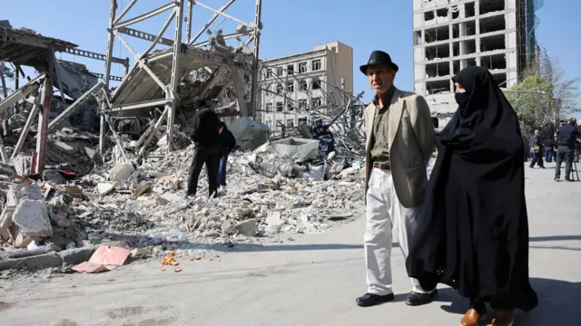 خبرنگاران در کنار یکی از محل‌های حمله حضور دارند و مردم هم از کنار آن عبور می‌کنند