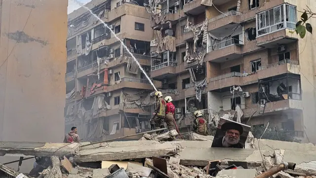 Bomberos extinguen un incendio en el lugar de un ataque aéreo israelí que tuvo como objetivo el barrio de Haret Hreik, en los suburbios del sur de Beirut, con un retrato del asesinado líder supremo de Irán, el ayatolá Ali Khamenei, visible entre los escombros, el 4 de marzo de 2026.