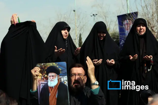 سيدات يشاركن في الدعاء بعد صلاة الجمعة في طهران، وفي مقدمتهم رجل يرفع صورة لخامنئي