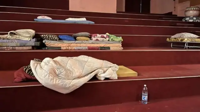 نیشنل تھیٹر کے اندر دو خاندان سٹیج کے سامنے بچھے گدوں پر سو رہے ہیں
