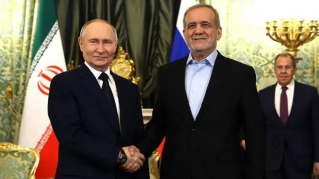 Путин и Пезешкиан пожимает друг другу руку на парадном фото.