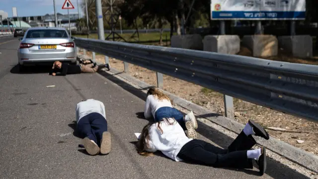 شهروندان اسرائيل هنگام هشدار حمله هوایی کنار جاده روی زمین پناه گرفته‌‌اند