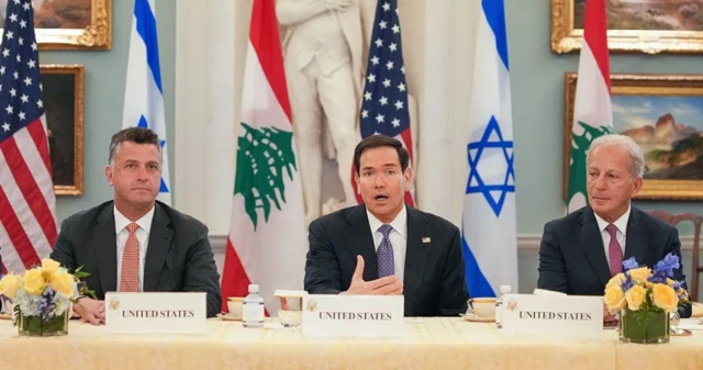 وزير الخارجية الأمريكي ماركو روبيو يجلس على طاولة وبجواره شخصان وفي الخلفية أعلام إسرائيل ولبنان والولايات المتحدة الأمريكية.