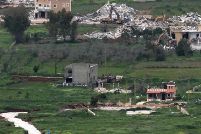 مدرعات إسرائيلية تحرس حفارات تقوم بهدم المباني في قرية ميس الجبل جنوب لبنان، كما شوهدت من الجانب الإسرائيلي من الحدود أمس