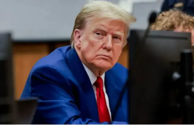 Perezida Donald Trump yambaye ikote ry'ibara ry'ubururu na kalvati itukura