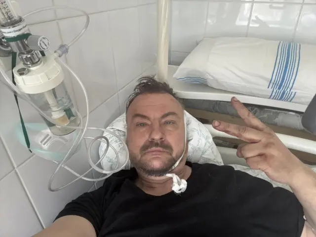 Мужчина на больничной койке с капельницей.