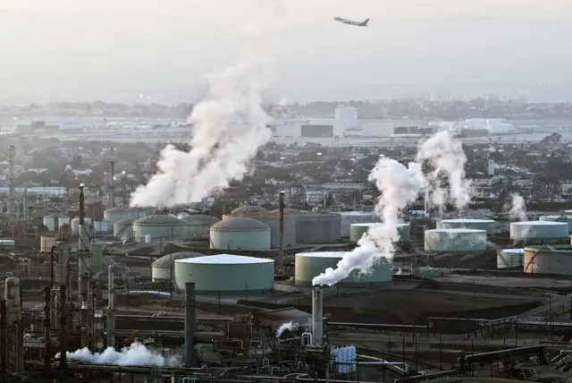 صورة جوية تُظهر مصفاة شيفرون إل سيغوندو يخرج منها دخان وهناك طائرة تحلق فوقها، والمصفاة واحدة من أكبر منشآت معالجة البترول في كاليفورنيا.