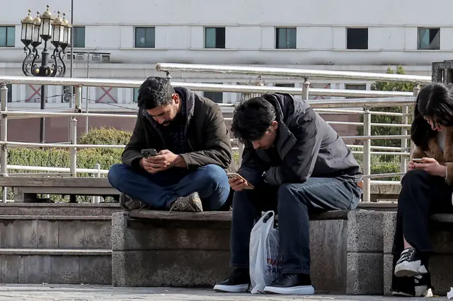 مواطنان إيرانيان يتابعان هواتفهما المحمولة