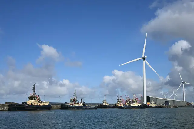 توربينات الرياح وقاطرات في نهر ميرسي داخل حوض ساندون هاف تايد، بجوار ملعب هيل ديكنسون في ليفربول، شمال غرب إنجلترا في 19 أبريل/نيسان 2026.