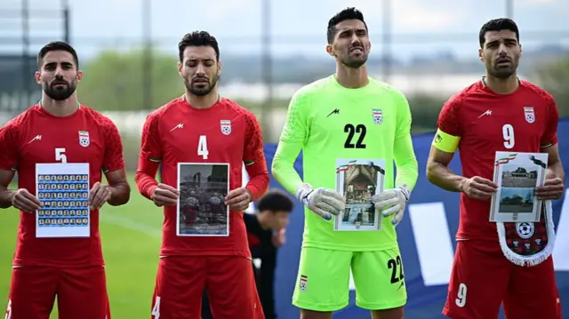 ईरान युद्ध के दौरान मारे गए बच्चों की तस्वीरों के साथ ईरानी फ़ुटबॉल टीम के खिलाड़ी (फ़ाइल फ़ोटो)