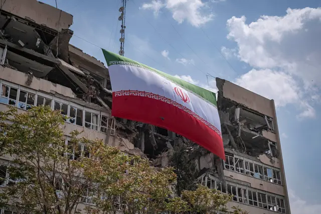العلم الإيراني يرفرف فوق مقر السلطة القضائية في طهران، الذي تضرر في عملية عسكرية. الصورة بتاريخ 20 أبريل/نيسان 2026.