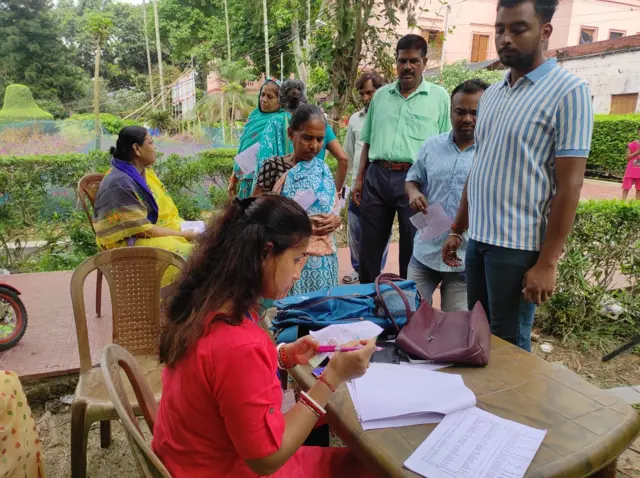 ভোটকেন্দ্রের বাইরে ভোটারদের পরিচয়পত্র দেখে তা মিলিয়ে নেওয়া হচ্ছে ভোটার তালিকার সঙ্গে