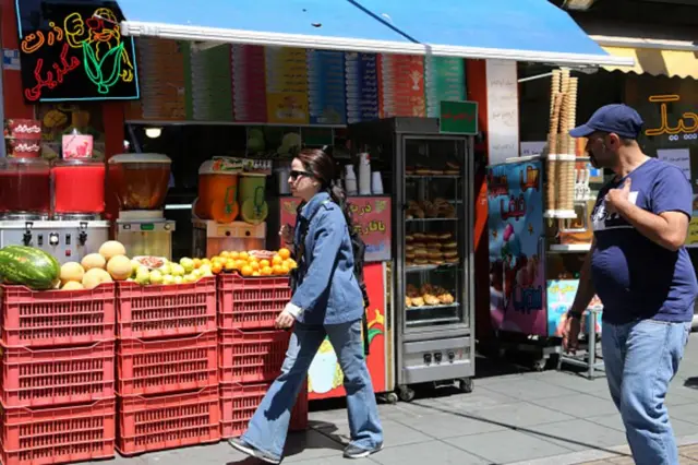 የሸቀጣ ሸቀጥ ሱቅ አጠገብ የሚያልፉ ሰዎች