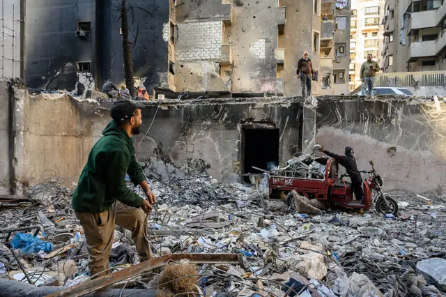 लेबनान में इसराइली हमले में तबाह इमारत से मलबा हटाते हुए लोग