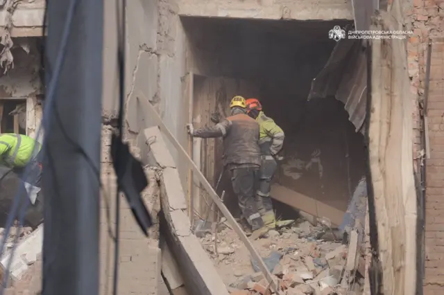 Два спасателя в разрушенном доме.