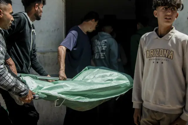 رجال يحملون جثة ملفوفة على نقالة عبر أحد شوارع مخيم جباليا، شمال قطاع غزة، في 25 أبريل/نيسان 2026. وقد قُتل الرجل برصاص القوات الإسرائيلية في مخيم جباليا شمال قطاع غزة، وسط تصعيد عسكري مستمر في المنطقة.