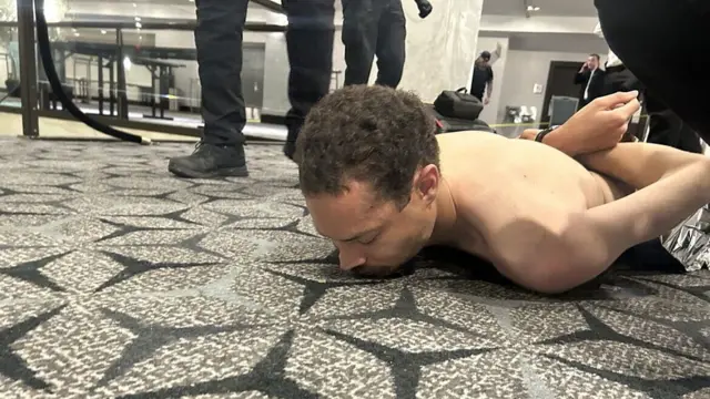 သေနတ်သမားကို ဖမ်းဆီးမိပြီလို့ ထရမ့်က ပြောတဲ့ Truth ဆိုရှယ်ပို့စ်မှာ တင်ထားတဲ့ ဓာတ်ပုံဖြစ်ပြီး အမျိုးသား တစ်ဦး ကြမ်းပြင်ကော်ဇောပေါ် ဝမ်းလျားမှောက်နေ