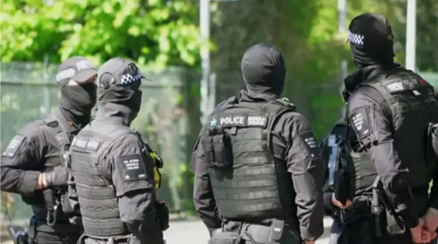 نیروهای پلیس با لباس نظامی سیاه ایستاده در فضای آزاد