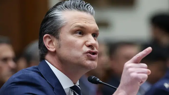 Ifoto ya Pete Hegseth, umushikiranganji ajejwe kwivuna abansi wa America, yambaye ikoti y'ubururu.