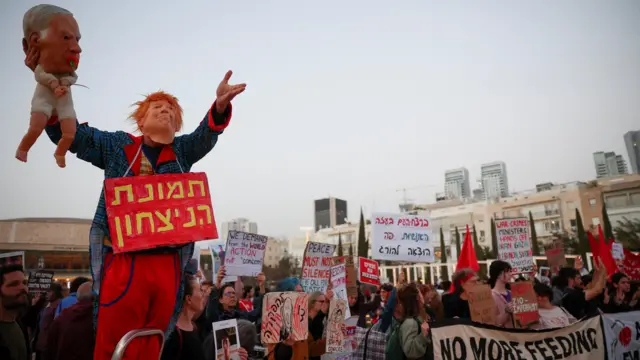 معترضی با ماسک ترامپ و عروسک نتانیاهو در قامت نوزاد در دست