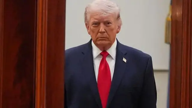 الرئيس الأمريكي دونالد ترامب يرتدي بدلة رسمية كحلية اللون وقميصاً أبيض وربطة عنق حمراء.