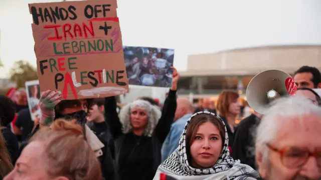 پلاکارد ضد جنگ علیه ایران، لبنان و فلسطین در دست معترضی در تل‌آویو