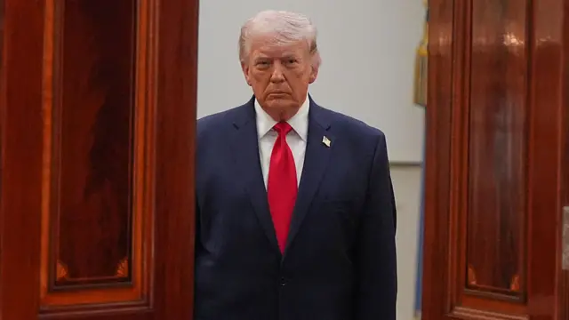 الرئيس الأمريكي دونالد ترامب مرتدياً بدلة رسمية كحلية اللون وقميصاً أبيض وربطة عنق حمراء