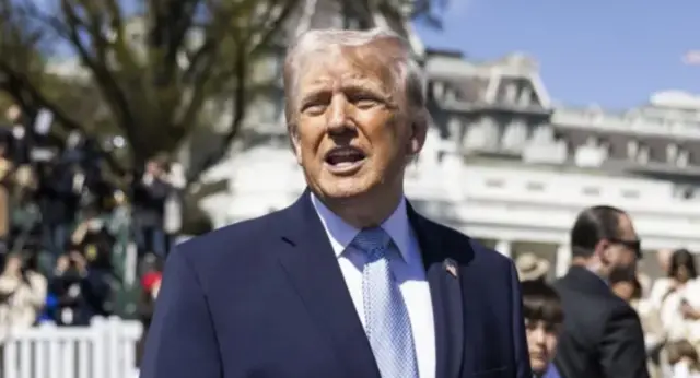 دونالد ترامب يرتدي بدلة كحلية اللون وربطة عنق زرقاء مع قميص أبيض ويتحدث في الخارج