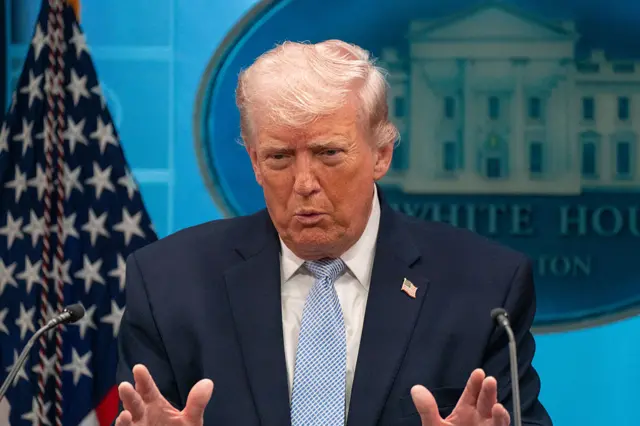Donald Trump habla en un atril con una bandera y el logo de la Casa Blanca detrás