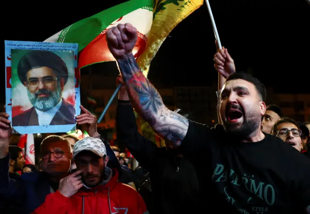 صورة تظهر شاباً إيرانياً يحتفل بعد إعلان وقف إطلاق النار بين الولايات المتحدة وإيران، ومن خلفه تبدو صورة المرشد الإيراني مجتبى خامنئي.