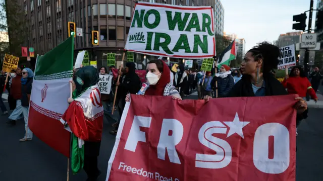 محتجون في واشنطن ينددون بالعمل العسكري الأمريكي ضد إيران ويرفعون العلم الإيراني وعدداً من اللافتات.