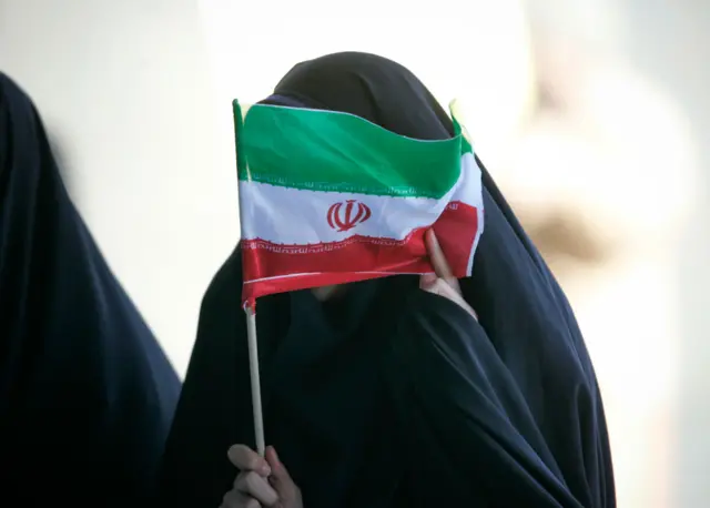 Picha ya mwanamke akiwa amebeba bendera ya Iran