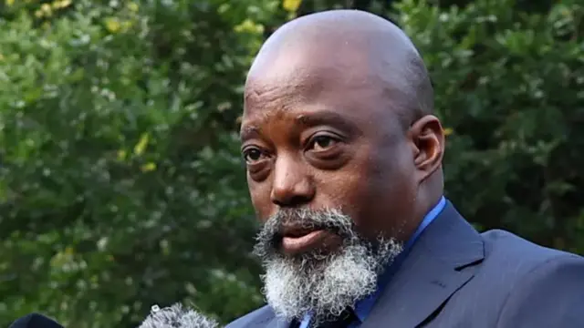 Joseph Kabila afite ubwanwa burebure burimo imvi, arimo kuvugira mu ndangururamajwi igaragara igice gito.