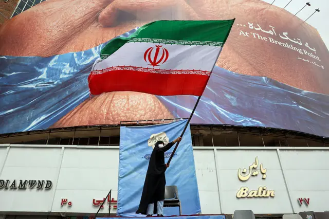 Mwanamke akiwa amebeba bendera ya Iran