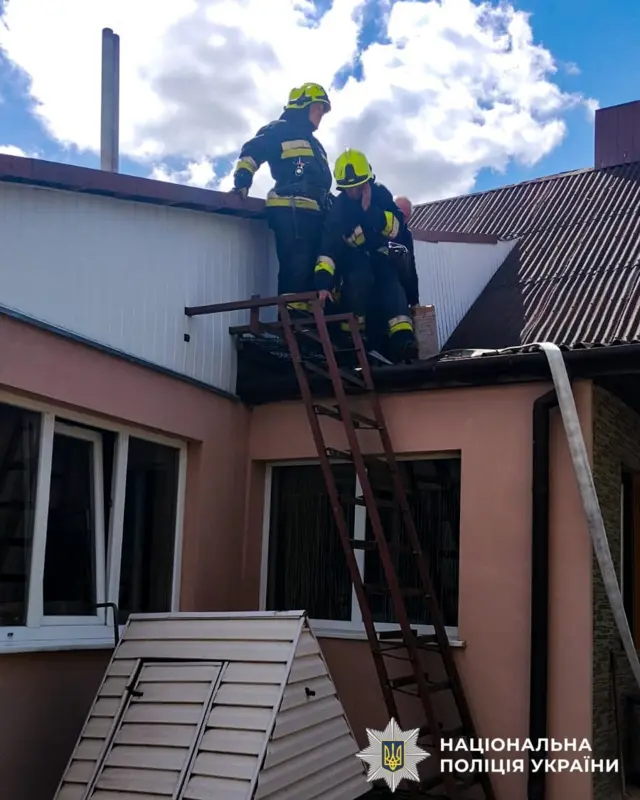 Двое спасателей на крыше здания.