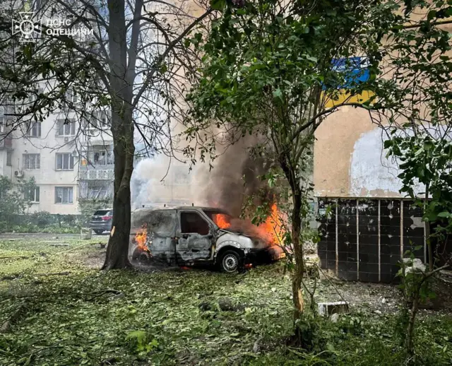 Горящий автомобиль около многоэтажного жилого дома.