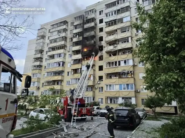 Пожарная машина с подъемником у многоэтажного дома с повреждениями