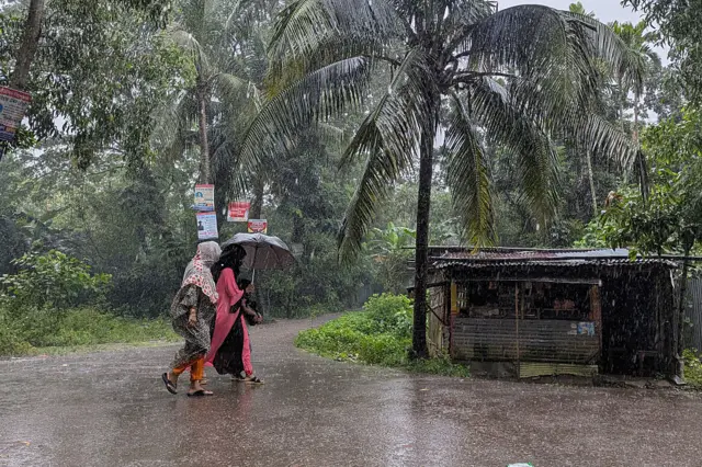 বৃষ্টিতে হেঁটে যাচ্ছেন দুই নারী