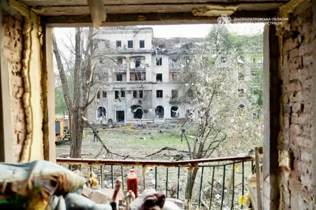 Вид из разрушенного окна на разрушенный дом.