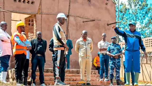 Prezida Evariste Ndayishimiye atunze urutoke ahantu hatagaragara, iruhande yiwe hari abantu benshi n'inyubakwa itaraherahezwa