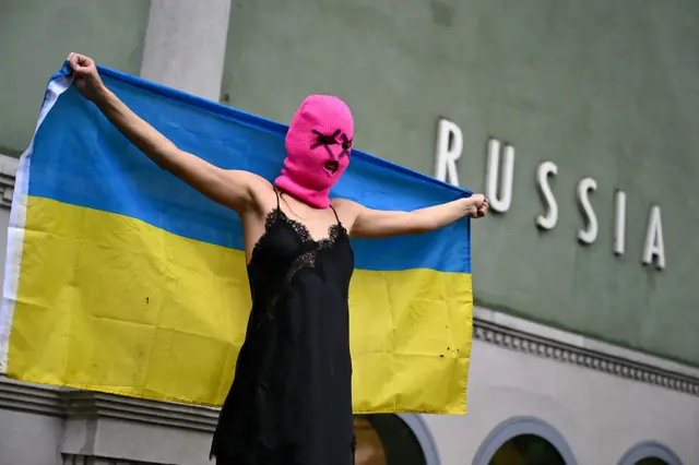 Активистка группы Pussy Riot с украинским флагом около российского павильона