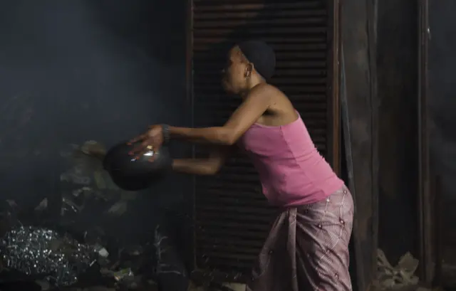 Umugore w'umudandaji mu isoko ya Kinama agerageza kuzimya aho akorera