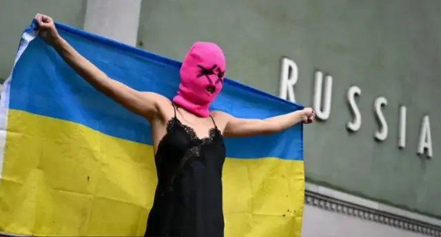 Активистка группы Pussy Riot стоит с развернутым флагом Украины