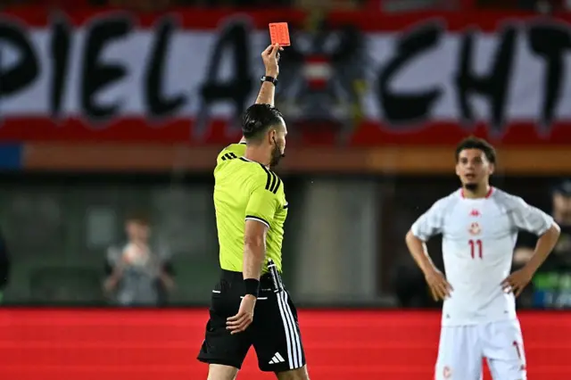 Árbitro mostrando cartão vermelho para um jogador usa uniforme branco