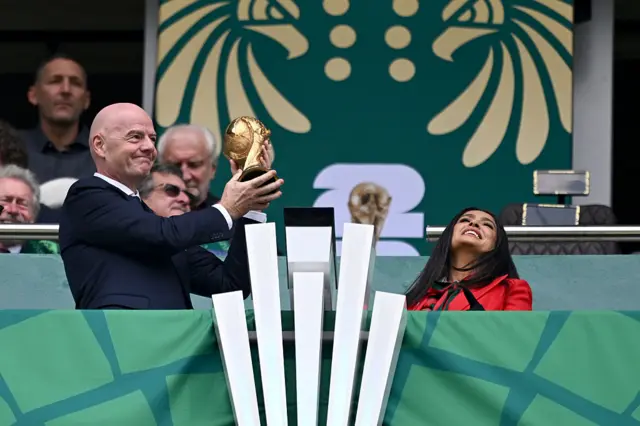 El presidente de la FIFA, Gianni Infantino, sostiene el trofeo de la Copa Mundial de la FIFA junto a Salma Hayek.