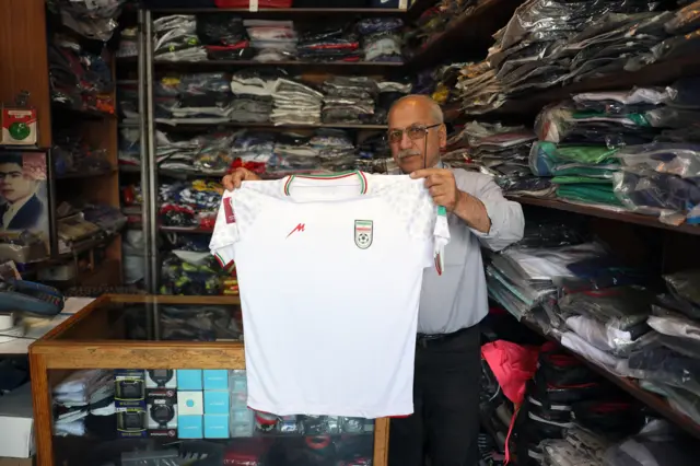 يعرض صاحب محل قميص المنتخب الإيراني لكرة القدم في كأس العالم 2026، وذلك في متجره الرياضي في طهران في 18 مايو/أيار 2026.